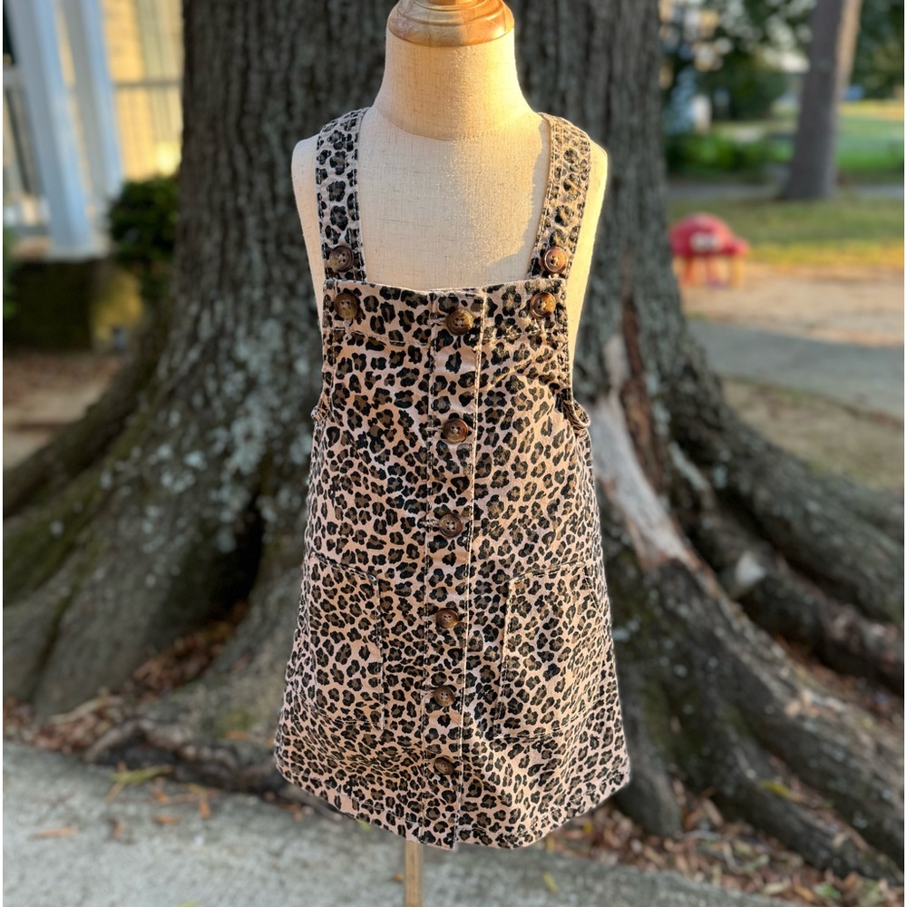 Leopard print denim dress with button up front, pockets, and adjustable straps